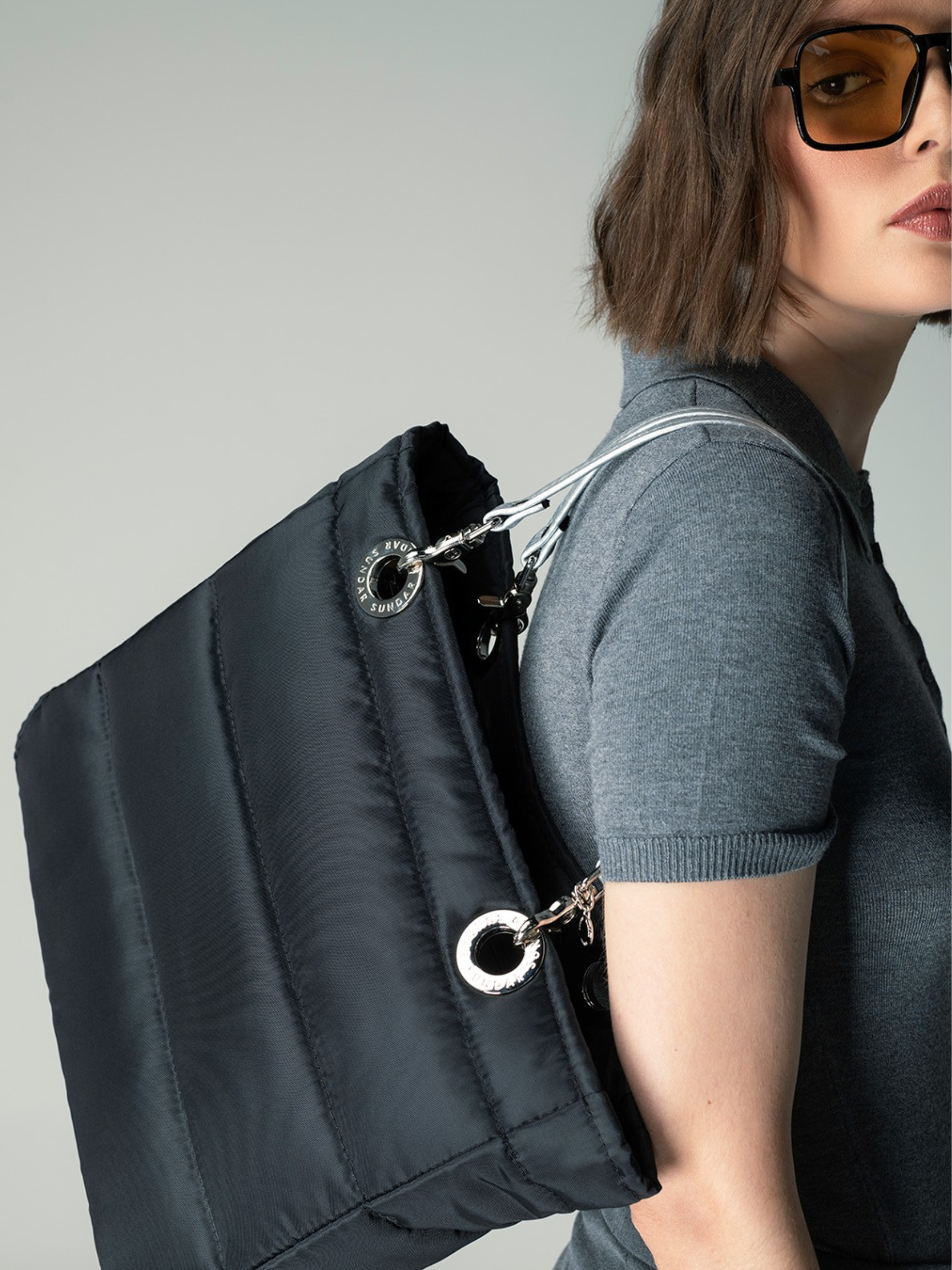 Detalle de la bolsa B&aacute;sica Sundar negra con asas met&aacute;licas y ojillos grabados